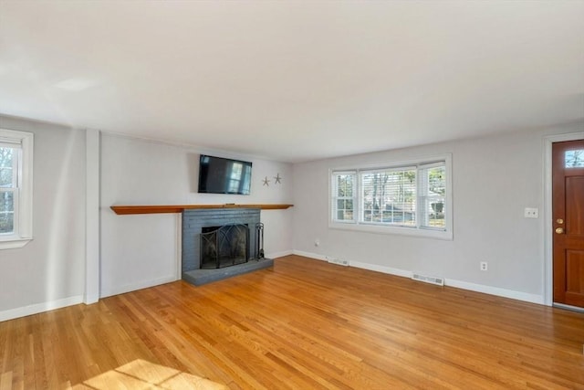 unfurnished living room with hardwood / wood-style flooring and a brick fireplace