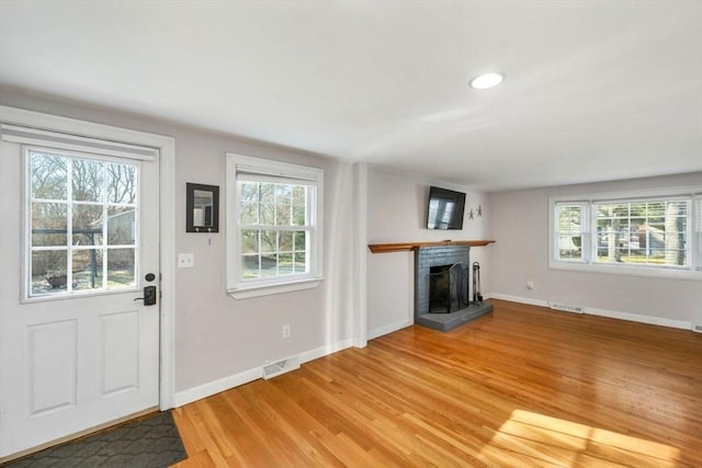 unfurnished living room with wood-type flooring, a fireplace, and a wealth of natural light