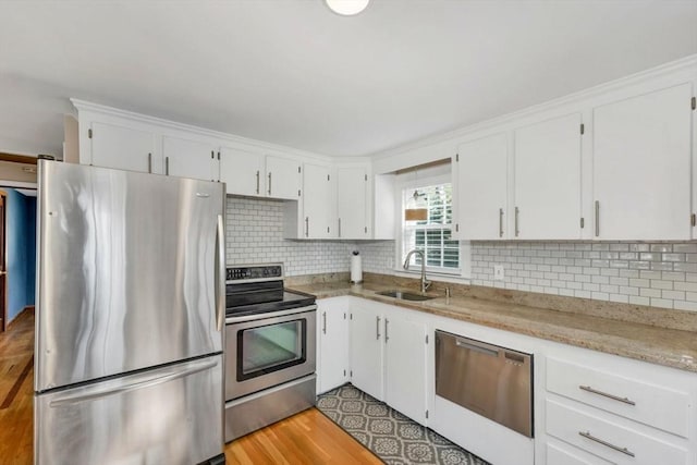 kitchen with appliances with stainless steel finishes, backsplash, white cabinetry, and sink