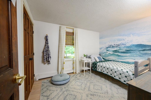 11 Williamsburg Ln, Scituate, MA 02066 - bedroom featuring light wood-style floors, a textured ceiling, multiple closets, and baseboard heating