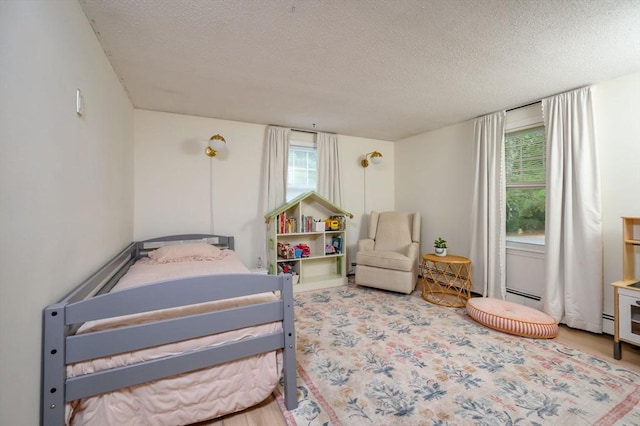 11 Williamsburg Ln, Scituate, MA 02066 - bedroom with a textured ceiling, wood finished floors, and baseboard heating