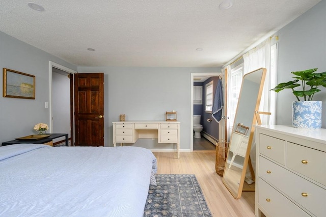 11 Williamsburg Ln, Scituate, MA 02066 - bedroom featuring light wood-style floors, a baseboard radiator, a textured ceiling, and ensuite bath