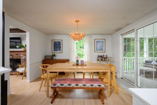 11 Williamsburg Ln, Scituate, MA 02066 - dining space featuring light wood-style floors, a chandelier, and a brick fireplace