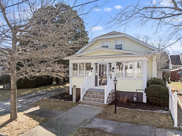 bungalow-style house with entry steps and fence