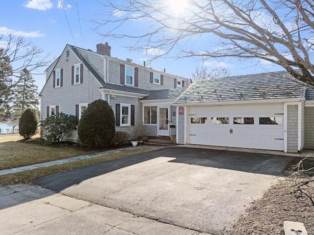 view of front of property with aphalt driveway, a garage, and a chimney