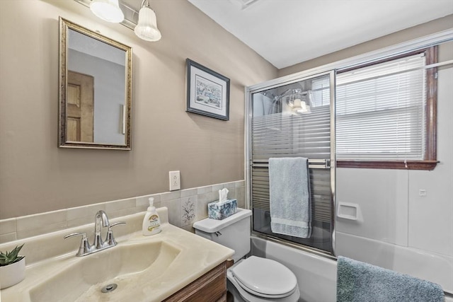 bathroom with combined bath / shower with glass door, toilet, and vanity