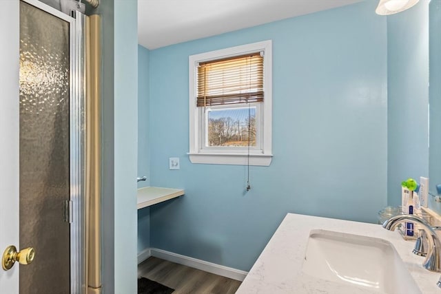 full bath with a sink, baseboards, wood finished floors, and a shower stall