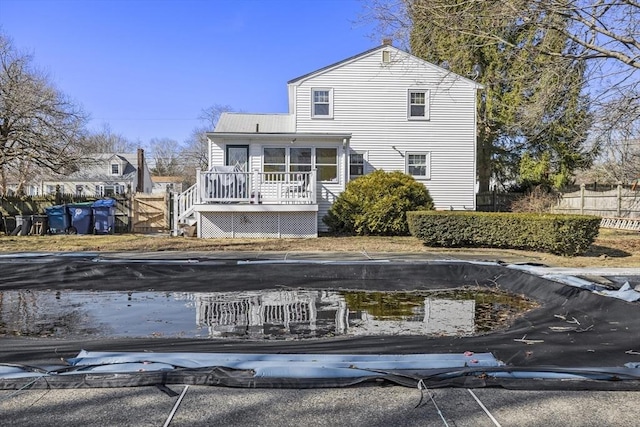 rear view of house with fence, a deck, and a sunroom