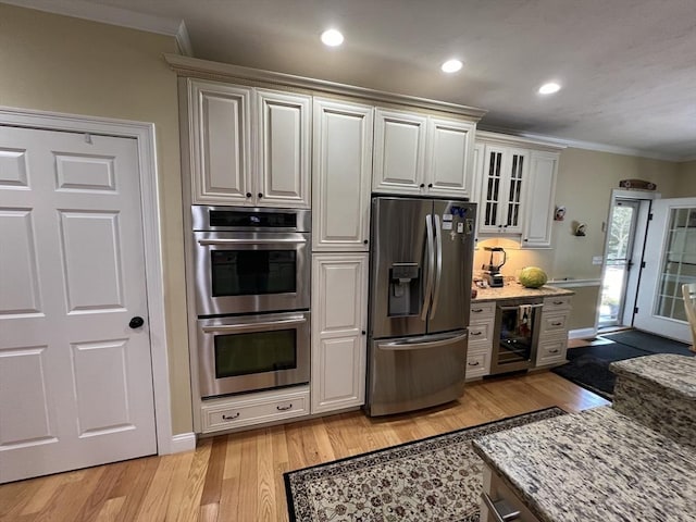 kitchen featuring beverage cooler, ornamental molding, light hardwood / wood-style floors, stainless steel appliances, and light stone countertops