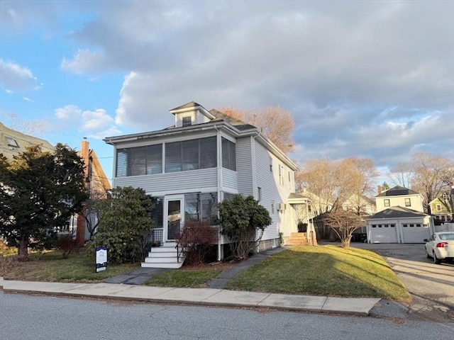 front of property with a garage, a front lawn, an outdoor structure, and a sunroom