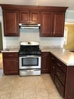 kitchen featuring kitchen peninsula, light tile patterned floors, and stainless steel range with gas stovetop