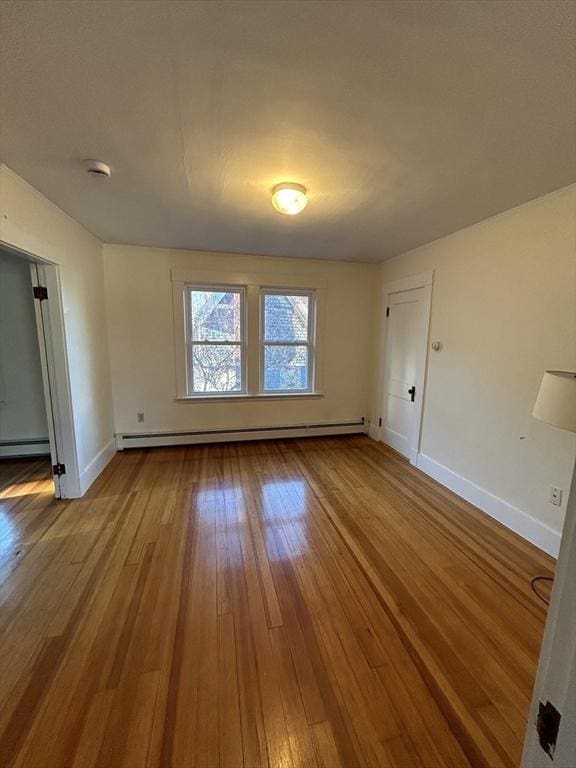 spare room with baseboard heating and wood-type flooring