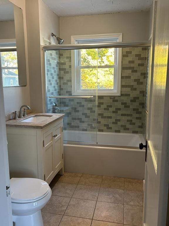 full bathroom featuring tile patterned floors, combined bath / shower with glass door, toilet, and vanity