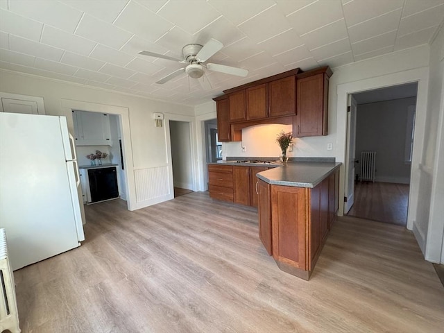 kitchen featuring kitchen peninsula, ceiling fan, white refrigerator, radiator heating unit, and light hardwood / wood-style floors