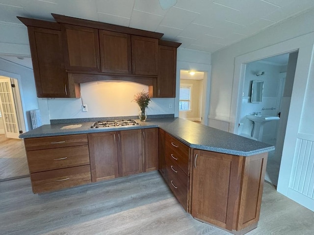 kitchen with kitchen peninsula, light wood-type flooring, and stainless steel gas cooktop