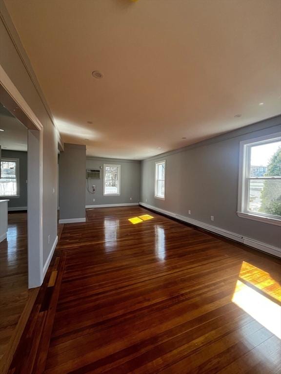 spare room featuring a wealth of natural light, wood finished floors, baseboards, and a wall mounted air conditioner