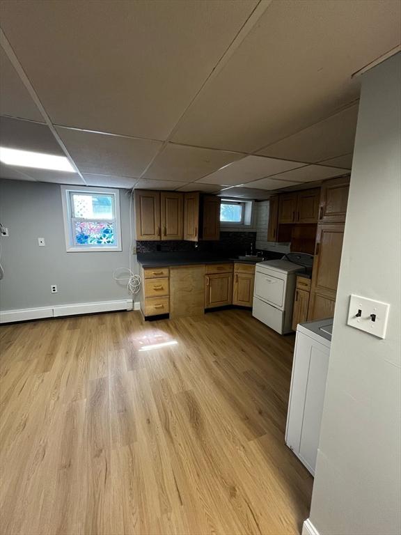 kitchen with stove, a drop ceiling, and light wood-style flooring