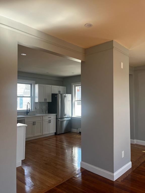 kitchen featuring a sink, light countertops, dark wood-style flooring, and freestanding refrigerator