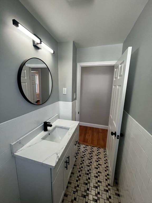 bathroom featuring wainscoting, tile walls, and vanity