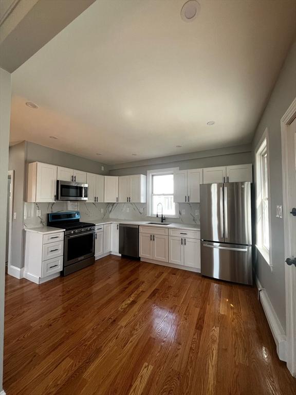 kitchen with a sink, stainless steel appliances, dark wood finished floors, and light countertops