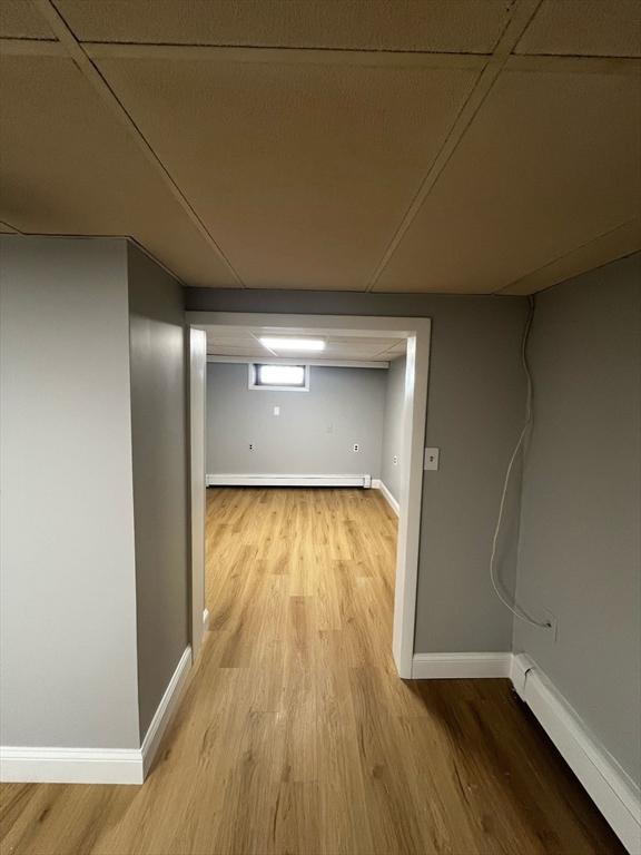 below grade area featuring light wood-style floors, baseboards, and a baseboard radiator