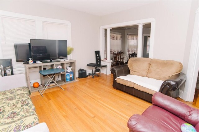 living area featuring decorative columns and wood finished floors