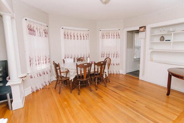 dining area featuring light wood finished floors and decorative columns