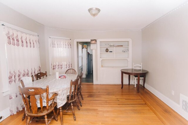 dining area with baseboards and light wood-style flooring