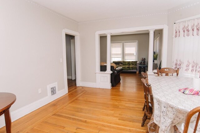 dining area with visible vents, light wood-style flooring, decorative columns, and baseboards