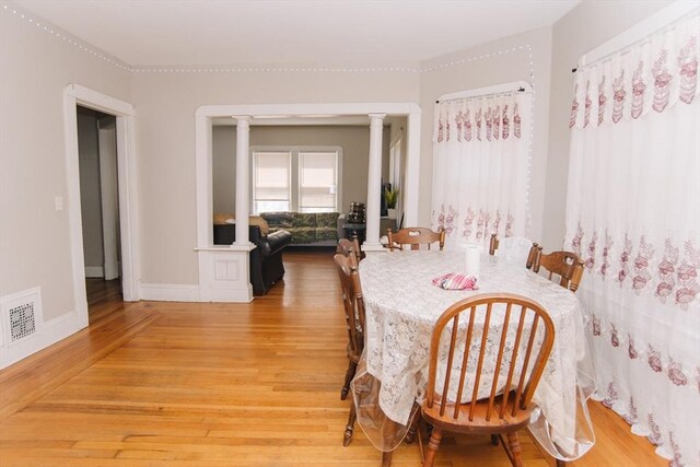 dining room featuring baseboards, decorative columns, light wood-style flooring, and visible vents