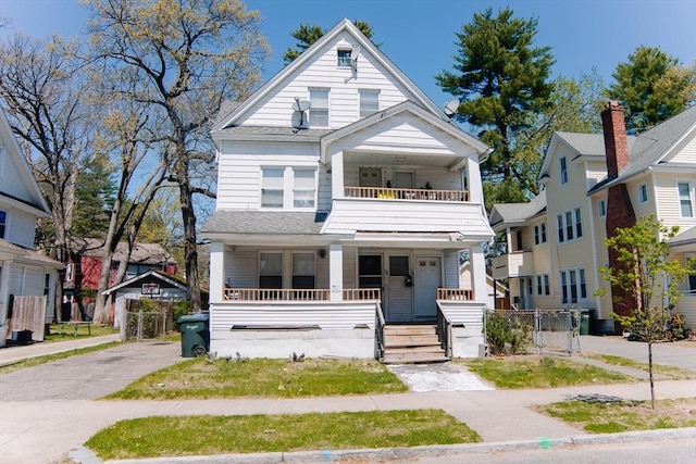 view of front facade with fence, a gate, covered porch, and a balcony