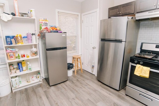 kitchen featuring decorative backsplash, dark brown cabinets, light wood-style floors, under cabinet range hood, and appliances with stainless steel finishes