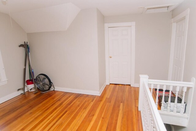 unfurnished bedroom featuring baseboards, attic access, and light wood finished floors