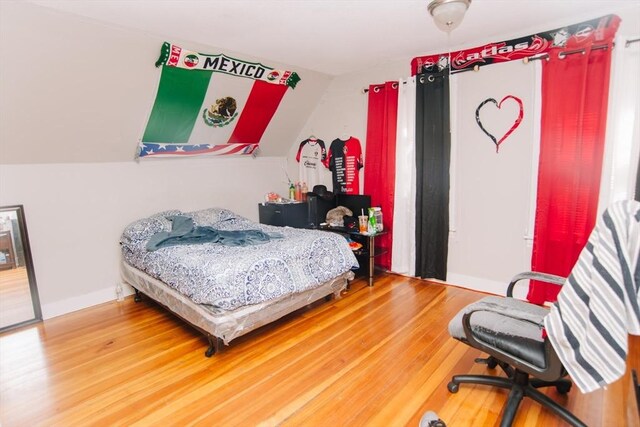 bedroom with baseboards, wood finished floors, and vaulted ceiling