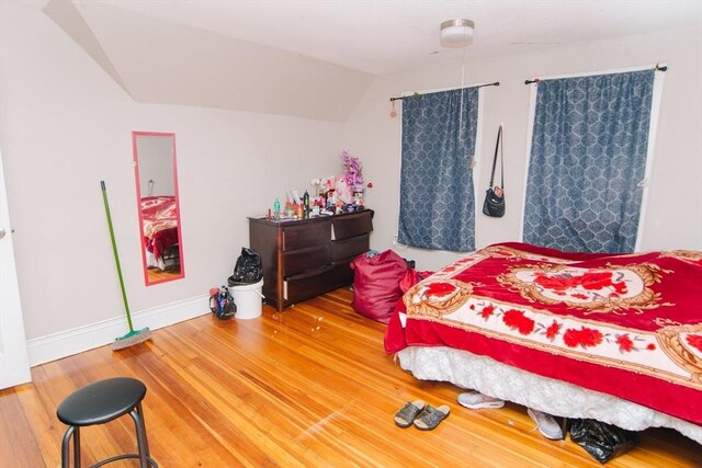 bedroom with baseboards, wood finished floors, and lofted ceiling