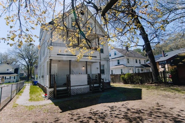back of house featuring a fenced backyard, a balcony, and a residential view