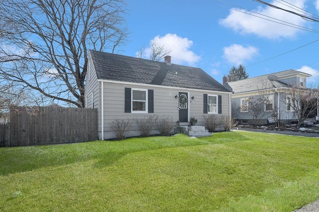 view of front facade featuring a shingled roof, a front lawn, fence, and a chimney