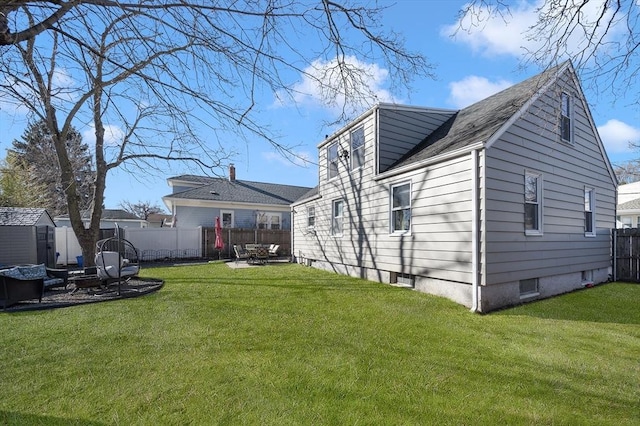 back of property with an outbuilding, a lawn, a storage shed, and fence