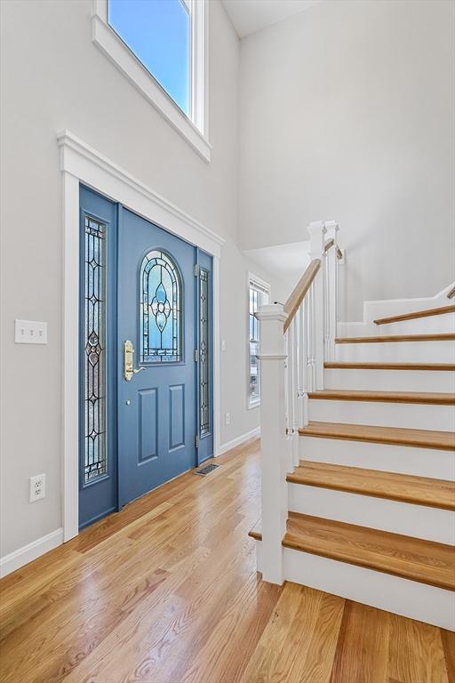 entryway featuring a towering ceiling and light wood-type flooring