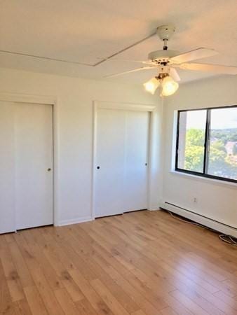 10 Williams St Unit 79, Watertown, MA 02472 - unfurnished bedroom featuring baseboard heating, light wood-style floors, and a ceiling fan