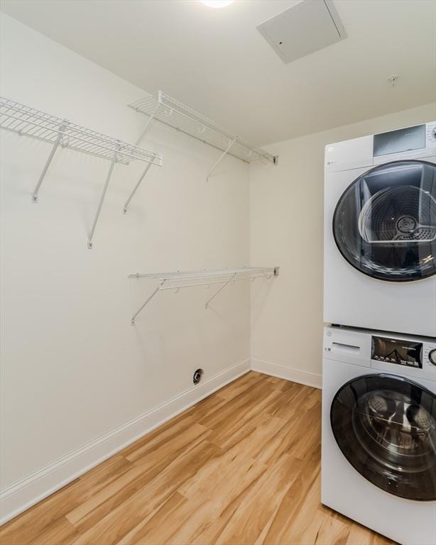 laundry room with wood-type flooring and stacked washer / dryer