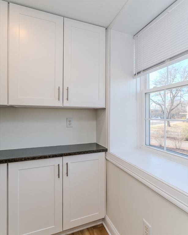 kitchen featuring white cabinetry, dark stone countertops, and light wood-type flooring