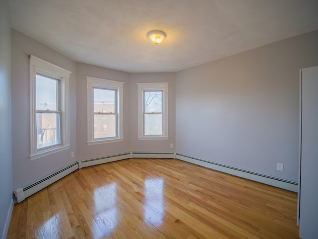 unfurnished room featuring baseboard heating and light hardwood / wood-style floors