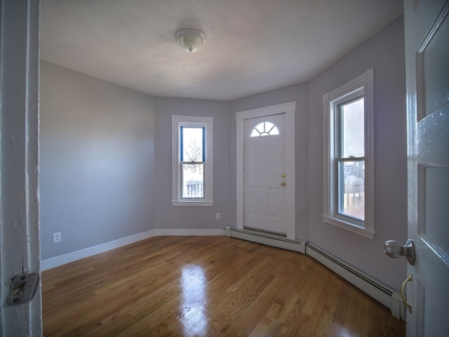 entrance foyer featuring a baseboard heating unit, light wood-type flooring, and a healthy amount of sunlight