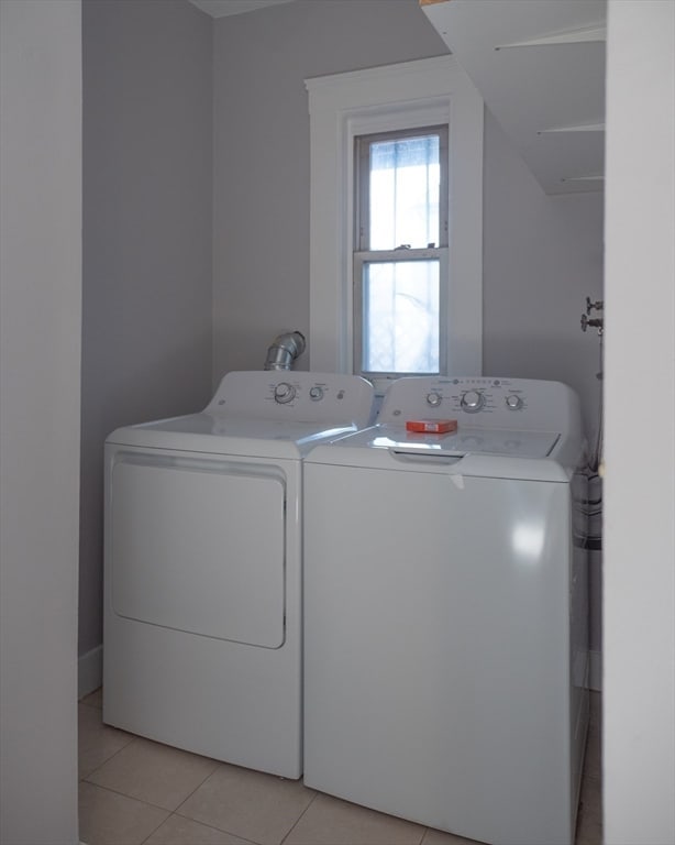 laundry room with washing machine and clothes dryer and light tile patterned floors