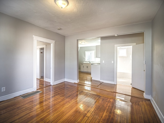 empty room with hardwood / wood-style floors and a textured ceiling