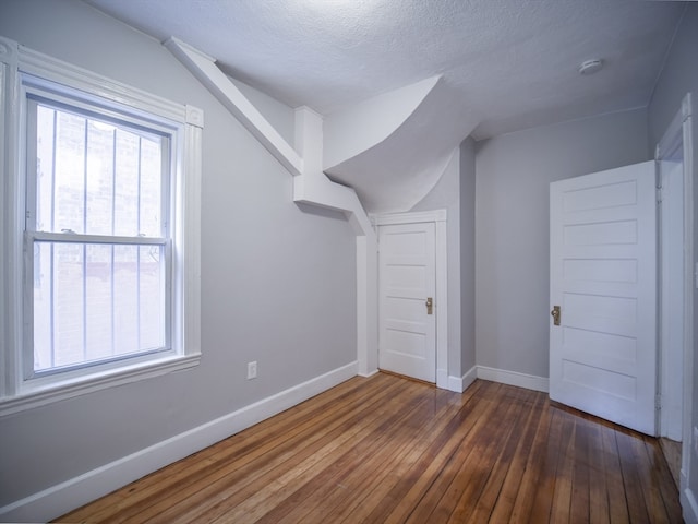 bonus room featuring dark hardwood / wood-style floors, a healthy amount of sunlight, and a textured ceiling