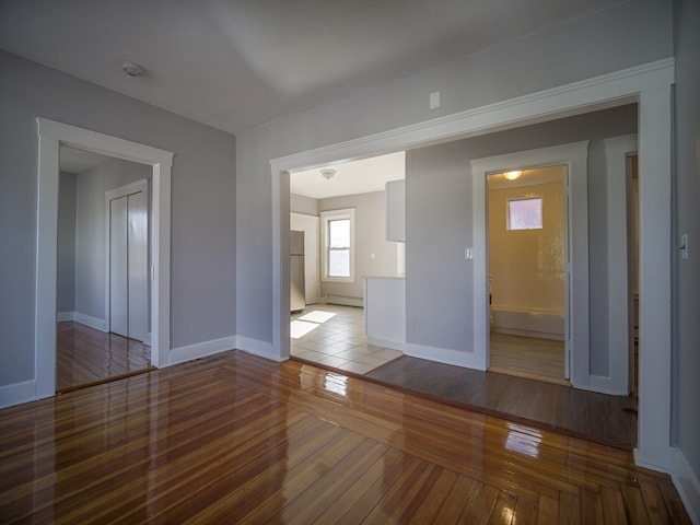 unfurnished room featuring hardwood / wood-style floors and a baseboard heating unit