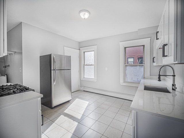 kitchen with white cabinets, stainless steel fridge, baseboard heating, and sink