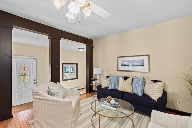 living room featuring baseboards, a baseboard radiator, decorative columns, and a ceiling fan